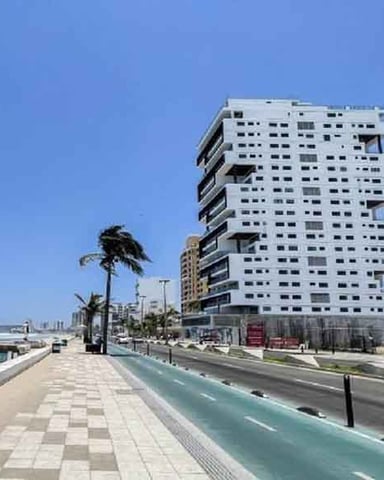 Casa de playa mexicana amarilla sobre la arena con palmeras y techo de palma