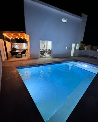 Private pool lit at night with outdoor dining area