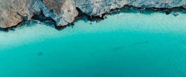 Aerial view of turquoise water meeting rocky desert cliffs on the Baja California coast
